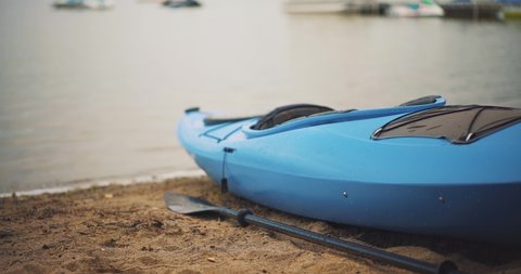 Empty Kayak and Paddle Sit Beached on Sandy Beach Shore with Calm Lake Waves in Distance ProRes 4k