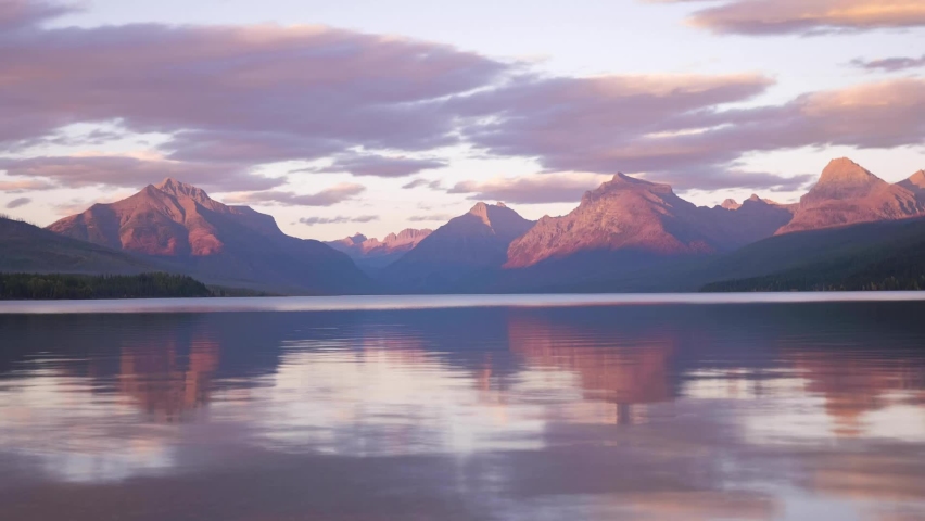 Timelapse panorama shot of Lake Mcdonald and lighting red rocky mountains after sunset. Clouds moving over the peak. Glacier National park,Montana. Royalty-Free Stock Footage #1067955518