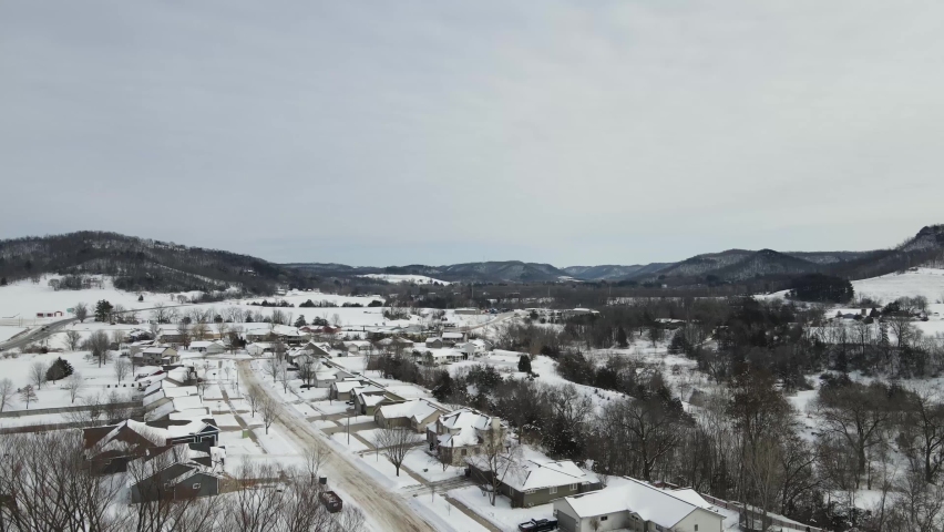 Slow pan just over the tree line of a rural suburban single road neighborhood in a snow-covered valley