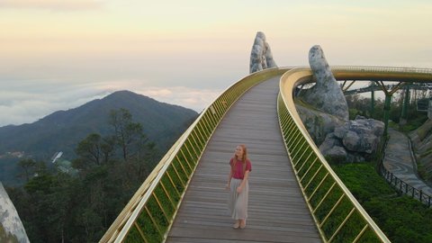 28.11.2020-Danang city, Vietnam: Slowmotion Aerial shot of a young woman walking on the Golden Bridge in the city of Danang. Tourist destination in central Vietnam. Travel to Vietnam concept
