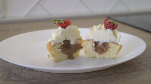 Cake Cut in Half on Plate. Fresh Bakery. Sweet Dessert. Shortcake with Chocolate Filling and White Airy Cream. Strawberry Cut into Pieces. Decoration. Sweetness. Chocolate Cream Pours Out On Plate