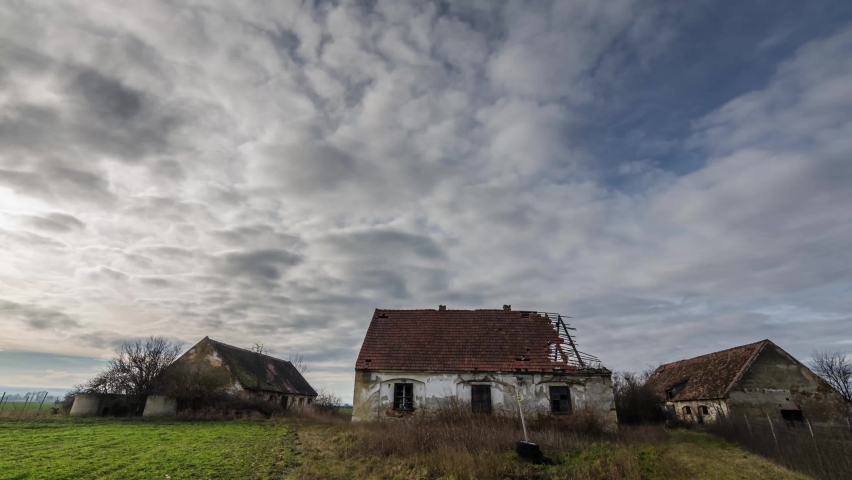 Time lapse of abandoned farm with clouds in the sky