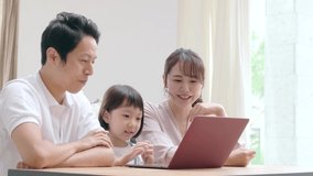 young Asian family using a laptop in the living room.