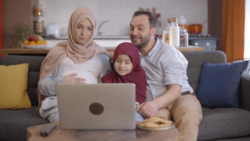 The Muslim woman wearing a hijab is happy when her daughter and husband video chat with their family and show her belly for the baby to be born. New sibling concept. Royalty-Free Stock Footage #1067966591