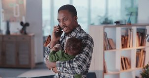 African american young daddy businessman talking in smartphone and calming in hands crying baby son. Babysitter. Busy lifestyle.