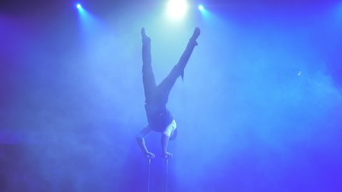 Young flexible acrobat executes tricks on a cube in circus