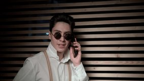 Young man in sunglasses talking on the phone. He expresses his displeasure and is indignant. Added film grain effect for cinematic video style.