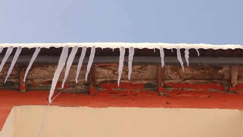 Erzurum in Turkey.
Roof ice dams.
Common view during winter -50 degrees Celsius.
Last days of winter, Beginning of spring.
Melting snow icicles, ice. 
Falling water drops under beams of sun.
Thawing