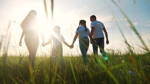 happy family walking together in the park silhouette. friendly family kid dream concept. happy family walking holding hands in the park on the grass at sunset. friendly family dream lifestyle together
