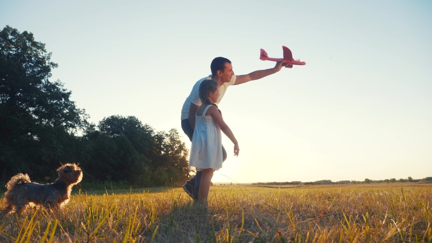 dad and daughter play with a toy airplane in the park in nature with a dog. kid dream concept happy family. dad and daughter play outdoors in the park. happy family with dream dog airplane in nature Royalty-Free Stock Footage #1067984969