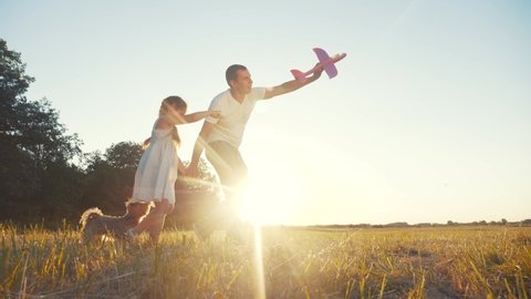 dad and daughter play with a toy airplane in the park in nature with a dog. kid dream concept happy family. dad and daughter play outdoors in the park. happy family with dream dog airplane in nature