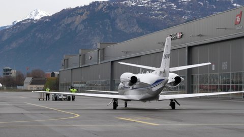 Sion , Switzerland - 12 20 2020: Ground Marshaller Guiding Private Jet to Parking at Sion Airport.