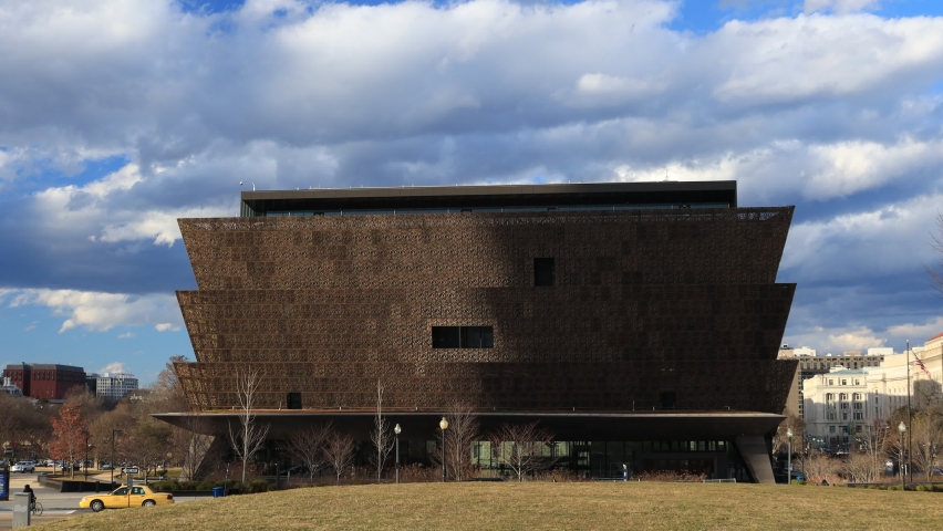 Washington, DC - USA - February 5 2021: The National Museum of African American History located on the National Mall seen on a bright winter day. Pedestrians and vehicles pass by as the camera pans.