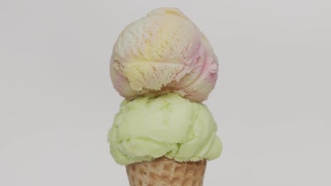 Time Lapse Rainbow on top Ice cream lime scoop in waffle cone on white background, Closeup Front view Food concept.
