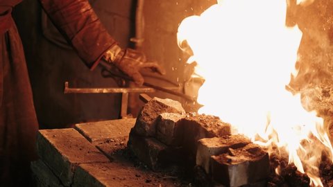Hot Metal in a Forge. Blacksmith pulls a hot piece of metal out of the burning ember. Forge workshop. Metalworking. Red-hot forge forge.