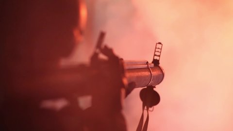 A shot from a grenade launcher in a dark room. Bright light and from the muzzle flash and explosion. The silhouette of a shooting soldier. Selective focus.
