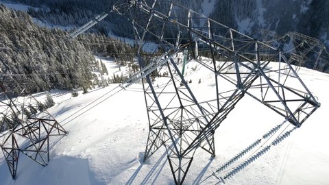 Electrical Grid Powder Lines Transfer Energy in Snowy Mountains Aerial View, Aerial view of utility towers in the backcountry wilderness of Washington State