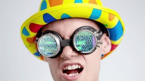 Glitching footage of young man wearing clown hat and spectacles with video flashing on lenses
