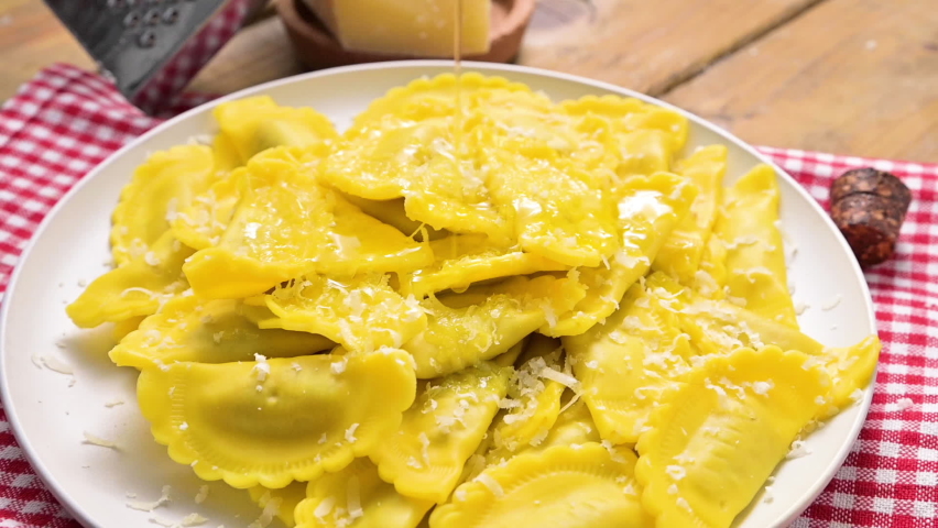 Italian Cuisine. Tartollini with cheese or meat on a plate with grated parmesan and olive oil poured. Traditional dish in italy, Emilia Romagna region. Homemade filled pasta.FullHD .slow-motion 