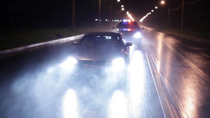The police chase the intruder in a sports car, a black SUV with flashing lights on overtakes him and tries to stop him. Outdoor front view of police traffic auto driving. Shot on the Russian Arm. Royalty-Free Stock Footage #1068008585