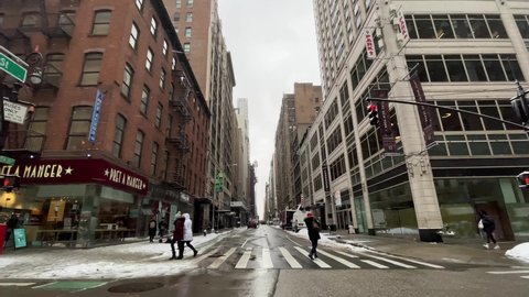 NYC, USA - FEB 19, 2021: shops and stores on 6th avenue - driving in winter - snowing Midtown Manhattan New York City.