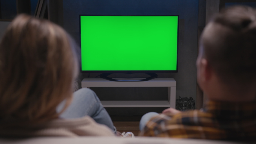 Family Couple Watches Green Screen TV Mock-up Sitting on Couch in Living Room Together. Rear View on Casual People who Watching TV Green Screen in Domestic Cinema. Looking TV Show or News in Home Rest | Shutterstock HD Video #1068017615