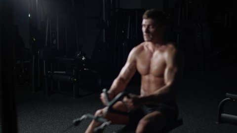 Athletic man in the Gym lifting blocks on rowing machine, training on block device and gym equipment, 4k Slow Motion.