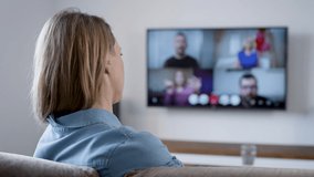 A woman is talking at home via video link. Video chat on TV with friends.