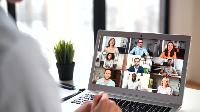 Back view of mixed-race woman waving at the laptop screen with people profiles, using an application for distance video communication with coworkers, webinar participants, meeting online in pandemic Royalty-Free Stock Footage #1068035957