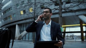 Mixed race businessman chatting to colleagues on smartphone sitting outside in the city, getting work finished
