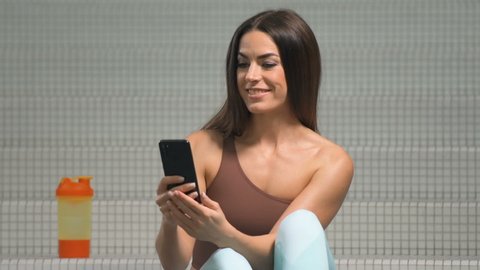 Woman with cell phone in gym at fitness workout. Health and lifestyle concept