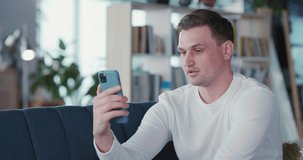 Young handsome adult man using mobile phone for webcam business talk video conference videochatting with corporate coworker at home.
