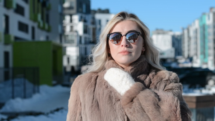 Beautiful blonde girl in sun glasses portrait in winter on the street of her city