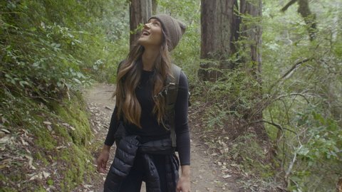 Young Woman Hiking Down Redwood Forest Trail and Looking at Trees in Awe