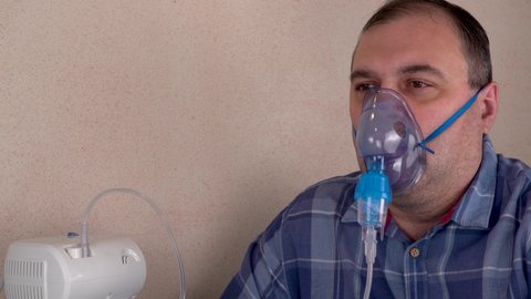 man breathes through a nebulizer mask. therapeutic procedures, carrying out inhalations. treatment of respiratory diseases and allergies. medical office, treatment room