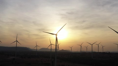 Aerial view of powerful Wind turbine farm for green energy production on beautiful sunset sky. Wind power turbines generating clean renewable energy for sustainable development. 4k footage.