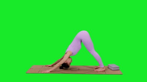 Attractive young yoga coach shows doing exercises on mat against green screen background, chroma key 4k pre-keyed footage