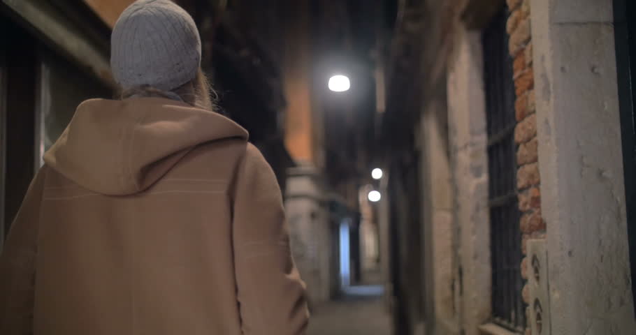 Woman is walking along the narrow street of an old town and taking photos with her tablet PC. Camera is following her.