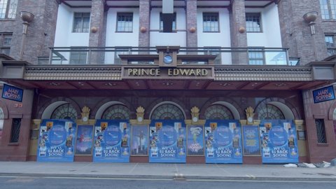 London, UK - February 10 2021: Static shot of closed doors of Prince Edward Theatre in London during Covid-19 lockdown with the odd person walking past