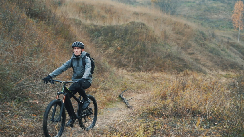 Male cyclist with helmet riding a mountain bike down the road in the countryside