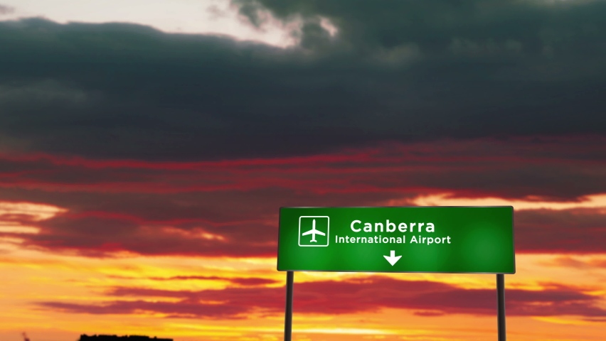 Airplane silhouette landing in Canberra, Australia. City arrival with airport direction signboard and sunset in background. Trip and transportation concept.