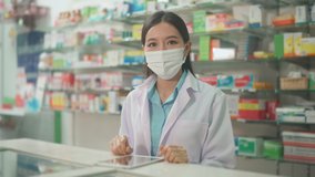 An asian woman pharmacist wearing lab coat and protective mask  using tablet to analytics medical data  in a modern pharmacy drugstore - Powered by Shutterstock - Get 15% off with code: PIKWIZARD15