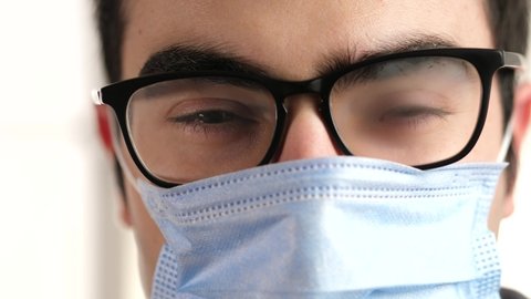 Man trying to breathe with a surgical mask on his face but his glasses are fogged and he can't see anything