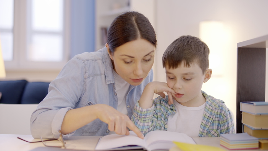 Young mother teaching son to read at home, helping to do homework, dyslexia Royalty-Free Stock Footage #1068055724