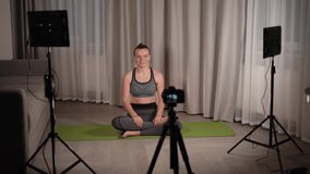 sports and vlogging concept - woman or blogger with camera on tripod record online yoga lesson at home. Video studio at home. LED light and camera on a tripod.