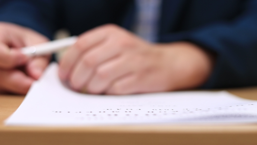 The businessman turns over the pages of the contract, reads and signs it.