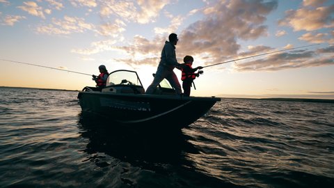 A father is helping his kids with fishing from a boat.