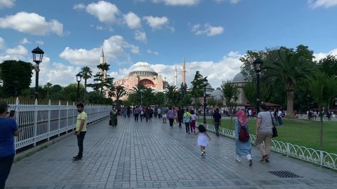 ISTANBUL - CIRCA JULY, 2019: Footage of tourists at famous city square called "Sultanahmet". Historical landmark "Hagia Sophia" is in the view. It is a sunny summer day. Camera moves forward.