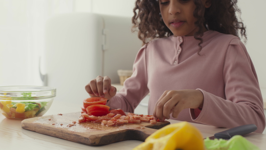 Close up shot of little african american girl trying sliced tomato and frowning her face, feeling disgusting taste, slow motion | Shutterstock HD Video #1068067184