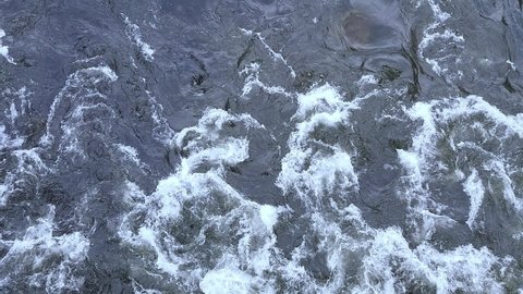 Turbulent gushing river water, vertiginous flow, swirling foamy water waves after heavy rain, turbid water rapids of Mur river, Austria
